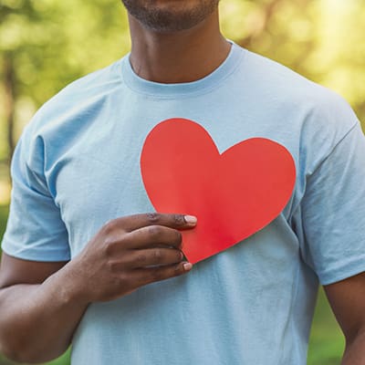 Black man holding red heart on his chest